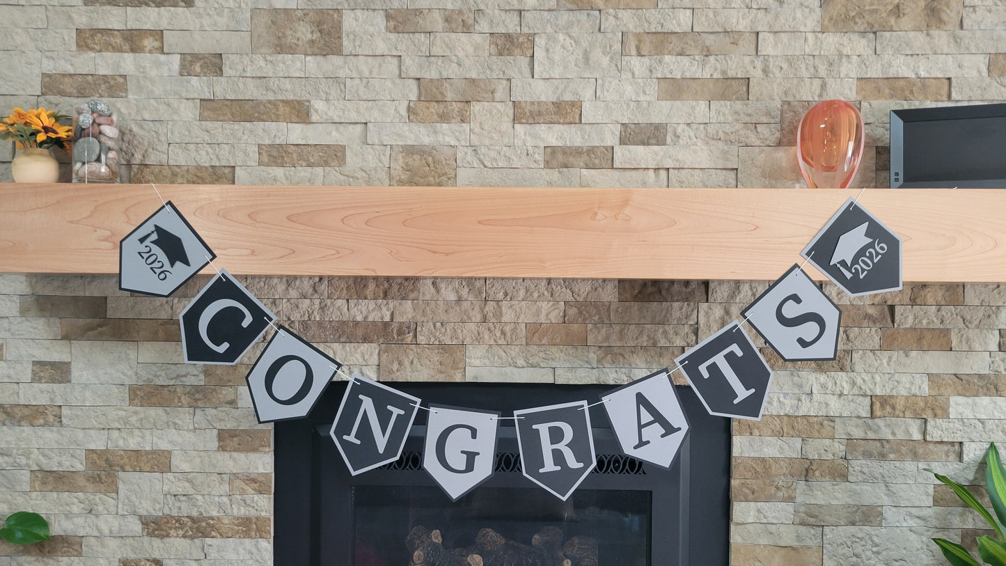 Graduation 'CONGRATS' banner on a fireplace with graduation cap and year design