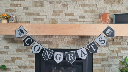 Graduation 'CONGRATS' banner on a fireplace with graduation cap and year design