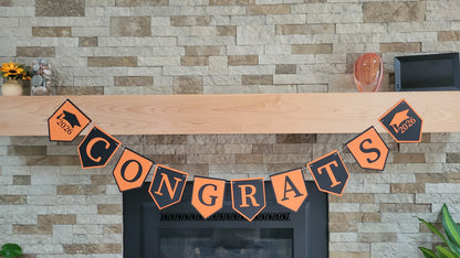 Graduation 'CONGRATS' banner on a fireplace with graduation cap and year design