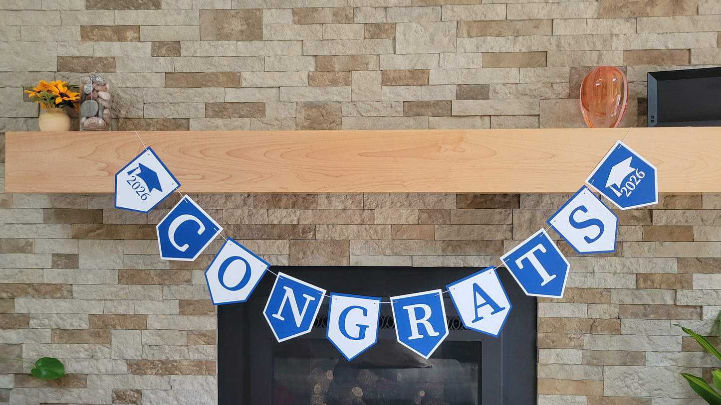 Graduation 'CONGRATS' banner on a fireplace with graduation cap and year design