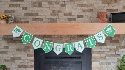 Graduation 'CONGRATS' banner on a fireplace with graduation cap and year design