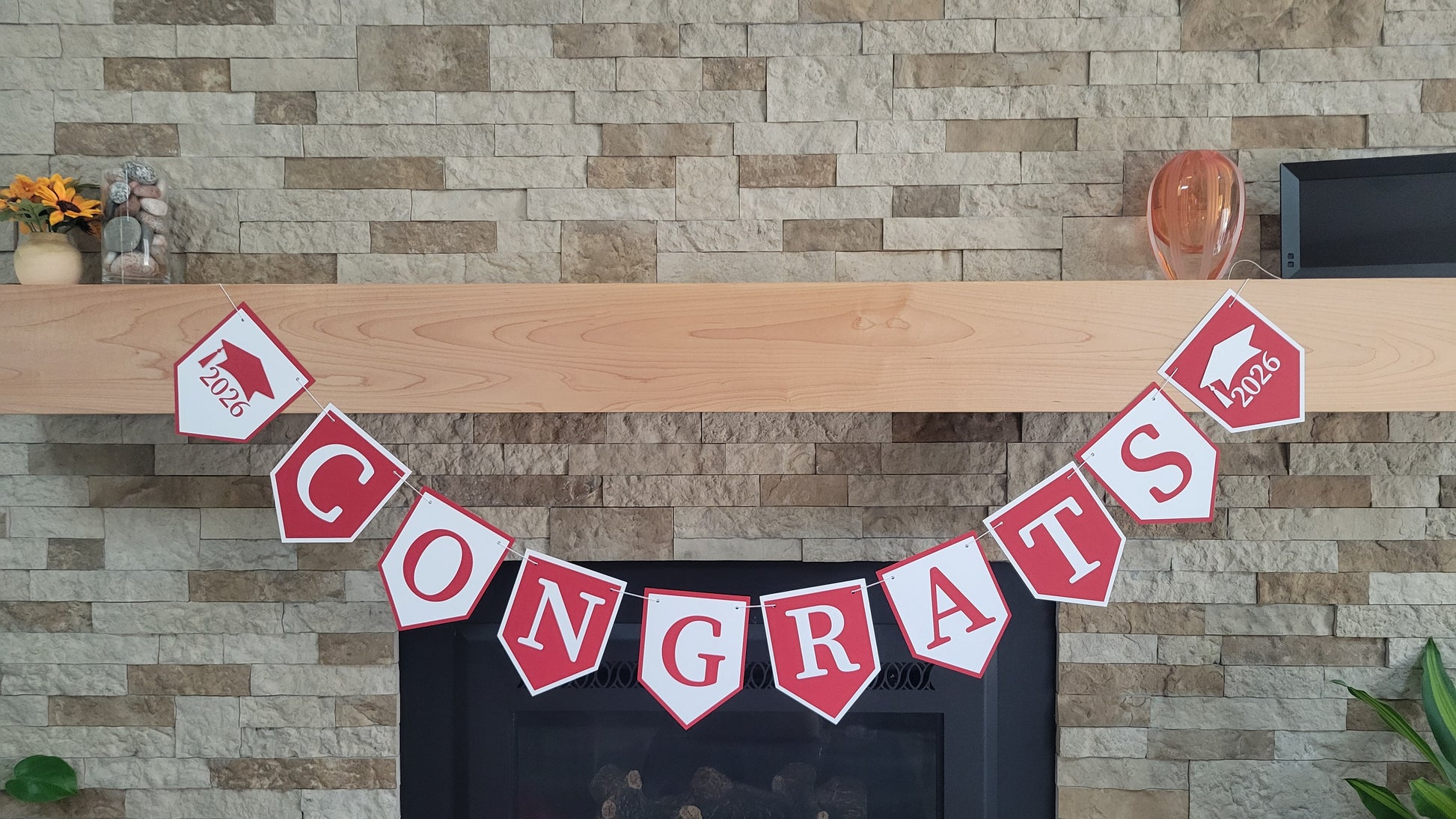 Graduation 'CONGRATS' banner on a fireplace with graduation cap and year design